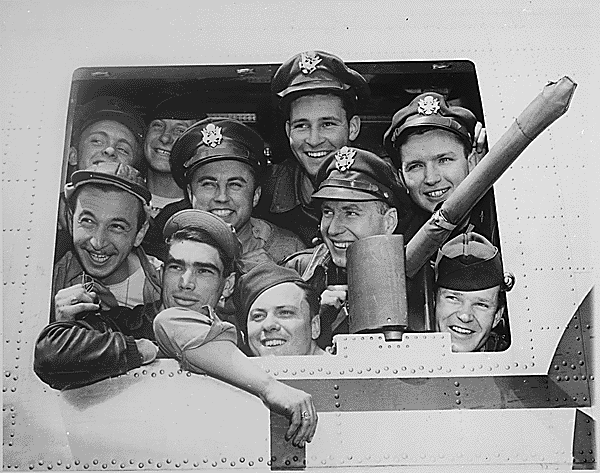 airmen smiling looking out of a bomber plane window